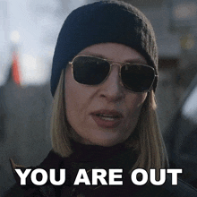 a woman wearing sunglasses and a beanie says " you are out "