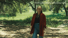 a woman in a red coat is standing in a park with a big bold beautiful journey written above her