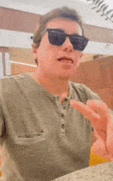 a man wearing sunglasses and a green shirt is pointing