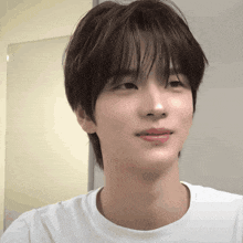 a young man wearing a white t-shirt looks at the camera