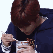 a man with red hair is eating noodles with chopsticks