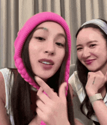 a woman wearing a pink beanie is sitting next to another woman