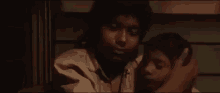 a woman is holding a child in her arms in a dark room in a movie .