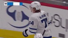 a hockey player with the number 74 on his jersey stands in front of a toronto maple leafs advertisement