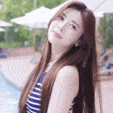 a woman in a blue and white striped swimsuit is standing in front of a pool