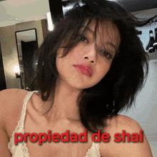 a woman in a white tank top with the words propiedad de shai above her