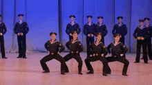 a group of men in sailor uniforms are standing in a row on a stage