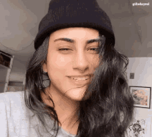 a woman wearing a black hat and a nose ring is smiling .