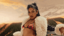 a woman wearing a fur coat and a bikini top has a tattoo on her chest that says " i love you "