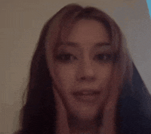 a close up of a woman 's face with pink hair and a blurry background .
