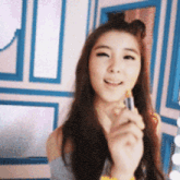 a young woman is holding a lipstick in her hand