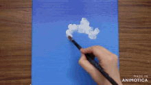 a person is painting a cloud on a blue canvas with the words made in animotica below it