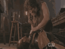 a man is laying on the floor next to another man with a cw logo in the background .