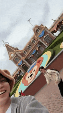 a man in a cowboy hat is taking a selfie in front of a building with a duffy bear on it