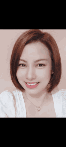 a woman wearing a white shirt and a heart necklace