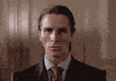 a man in a suit and tie is sitting in a chair and looking at the camera .