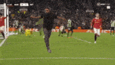 a man with a beard is jumping in the air on a soccer field with players in the background .