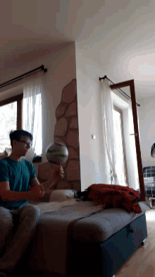 a boy sitting on a couch holding a ball