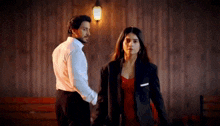 a man in a suit and a woman in a red dress are holding hands .