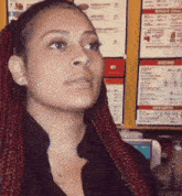 a woman with red braids is standing in front of a menu for biggie 's