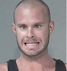 a man with a beard and a shaved head is smiling with his mouth open .