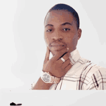 a man wearing a watch and a ring on his finger is looking at the camera .
