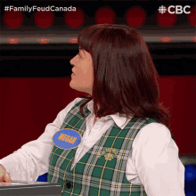 a woman in a plaid vest has a name tag that says mean