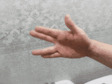 a close up of a person 's hand against a gray wall