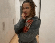 a young man with dreadlocks is wearing a grey hoodie with the number 19 on the sleeve