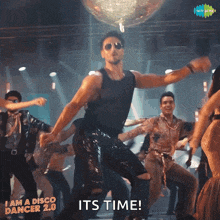 a man is dancing in front of a disco ball with the words " its time " on the bottom