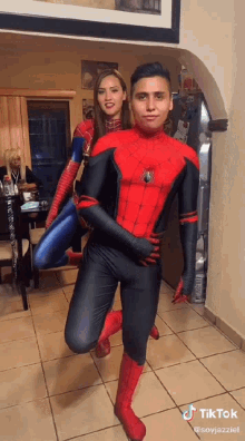a man in a spiderman costume is carrying a woman in a spiderman costume .