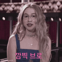 a woman with blonde hair and glasses is wearing a choker and a blue tank top