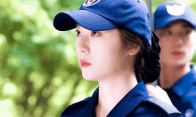 a woman in a police uniform is wearing a blue baseball cap
