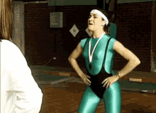 a woman in a green leotard with a medal around her neck stands in a gym