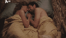 a man and a woman laying in bed with a hd logo in the background