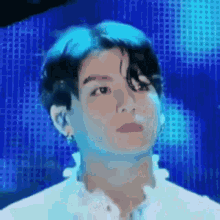a close up of a person 's face with a blue background and a white shirt .