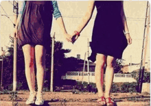 two women standing next to each other holding hands in a field