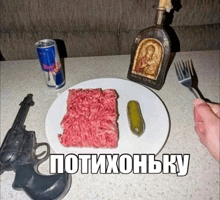 a white plate with meat and a pickle on it with a red bull can on the table