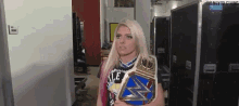 a woman with blonde hair is holding a wrestling championship belt .