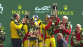 a group of men holding trophies in front of a rolex logo