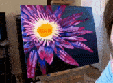 a painting of a purple flower with a yellow center on an easel