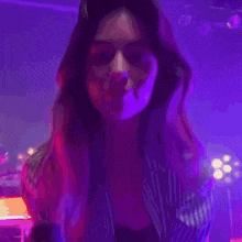 a woman in a bra and striped shirt is dancing in a dark room