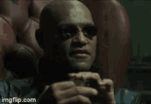 a bald man wearing sunglasses is sitting in a chair with imgflip.com in the corner