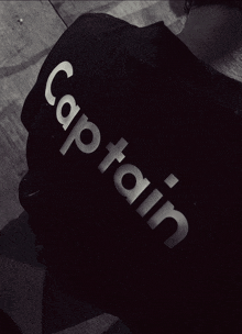 a person wearing a black shirt that says captain on it