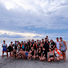 a group of people are posing for a picture on a beach and one of them is wearing a shirt that says puma