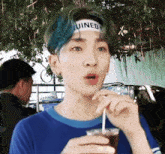 a young man with blue hair wearing a headband that says ruined drinking from a cup