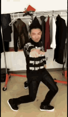 a man is dancing in front of a rack of clothes