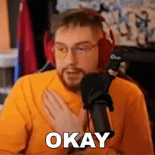 a man wearing headphones and glasses is holding his chest and saying okay