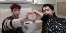 two young men are making a heart shape with their hands