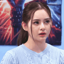a close up of a woman 's face with a blue sweater on